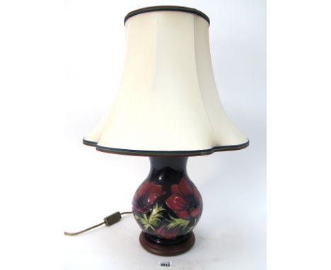 A Moorcroft Pottery Table Lamp, painted in the Anemone pattern with pink and purple flowers against a dark blue ground, on a 