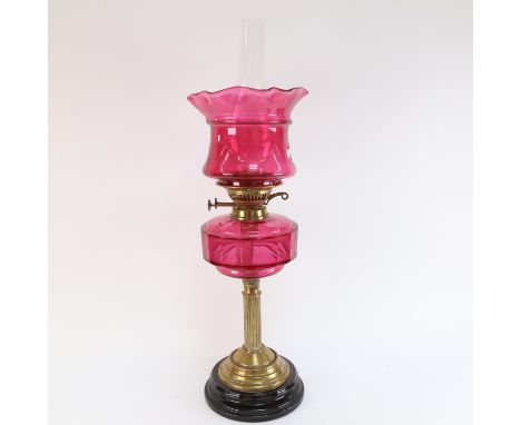 A Victorian cranberry glass and brass-mounted oil lamp, with cranberry shade, overall height 64cm (A/F, font and shade are bo