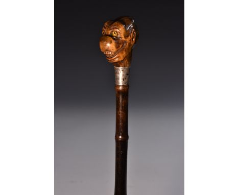 A Victorian novelty silver-mounted bamboo walking stick, the pommel carved as a grotesque anthropomorphic monkey inset with g