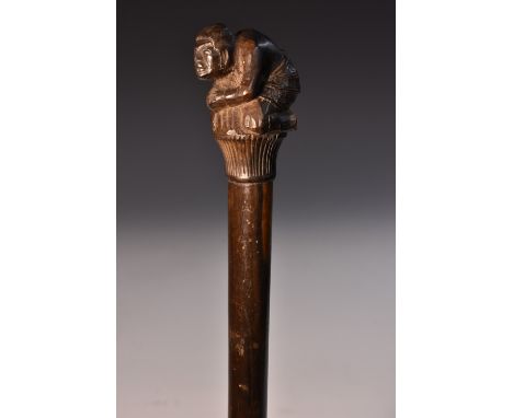 A Japanese hardwood walking stick, the pommel carved as a traditionally dressed peasant, kneeling in prayer on a lotus base, 