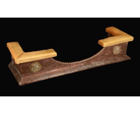 An Arts and Crafts copper mounted club fender, upholstered angles, bowed frieze applied with a pair of brass roundels, on a t