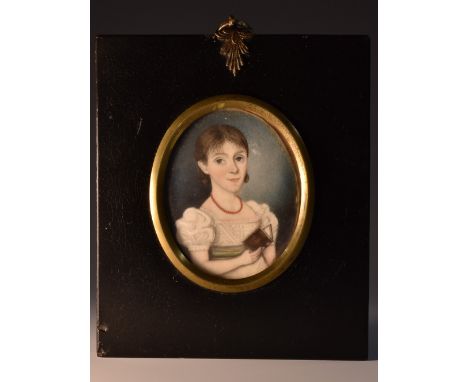 English School (early 19th century), a portrait miniature, of a young girl reading a book, bust length, wearing a coral neckl