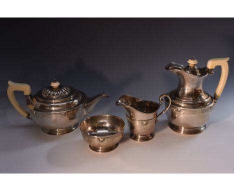 A George VI silver four piece pedestal tea service, comprising teapot, water pot, sugar basin and helmet shaped cream jug and