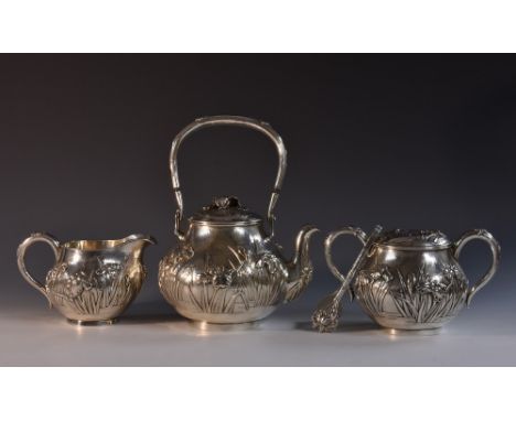 A Japanese silver three piece tea service, comprising teapot, milk jug and covered two-handled sugar bowl, each in relief wit