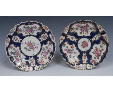 A pair of Worcester shaped circular plates, decorated with fan and vase shaped reserves with colourful summer flowers on a sc