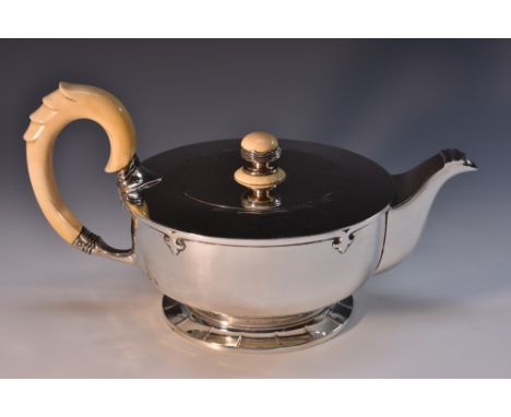 A substantial Art Deco silver teapot, flush-hinged cover, ivory scroll handle and finial, applied with cut-card leafy pendant