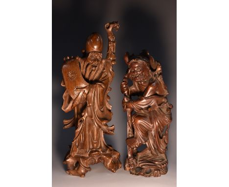 A 19th century Chinese hardwood carving, of Shou Lao, the elderly sage unfolds a scroll of wisdom, wearing flowing robes, his