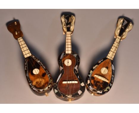 A tortoiseshell novelty model, of a guitar, inlaid with mother of pearl lozenges, 13.5cm long; mandolins, similar (3)