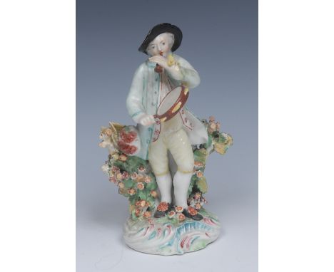 A Derby Patch Mark figure, of a Musician, he stands wearing a broad brimmed hat, light blue jacket and yellow breeches, holdi