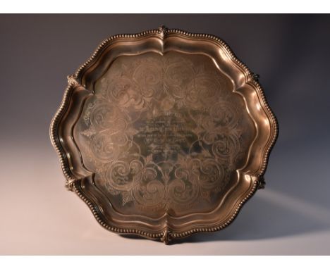 A Victorian silver shaped circular salver, of George III design, beaded fluted border, the field engraved with a band of scro