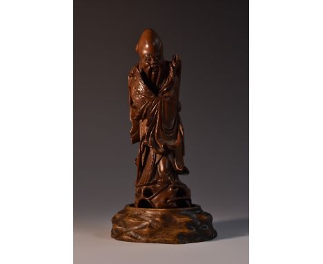 A Chinese boxwood carving, of Shou Lao, he stands, holding a scroll. 18cm high, 19th century, hardwood stand