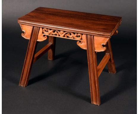 A Chinese hardwood stool or low table, oversailing rounded rectangular top above a shaped and pierced frieze, outswept legs, 