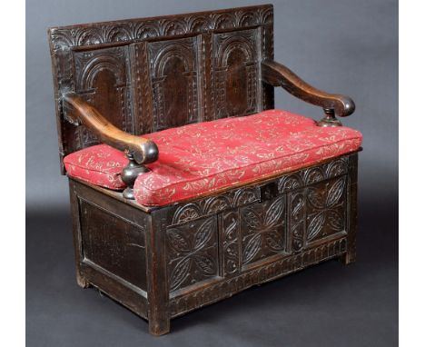 An '18th century' oak settle, rectangular three-panel back carved with leafy lunettes and architectural arches, the 'blanket 