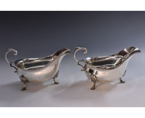 A pair of George V silver sauce boats, of George III design, acanthus-capped flying scroll handles, gadrooned borders, pad fe