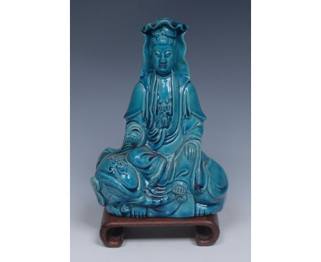 A 19th century Chinese monochrome earthenware figure, of Guanyin, the veiled deity sits on the back of a recumbent elephant, 