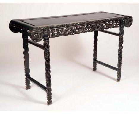 A Chinese hardwood altar table, panelled top with scroll ends, above a shaped frieze pierced and carved with ferocious dragon