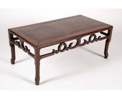 A Chinese padouk wood rectangular low tea table, panelled top above a deep pierced frieze, scroll legs, 31cm high, 76cm wide,