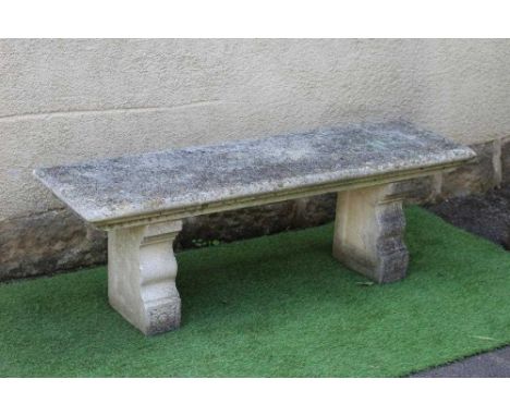 A CAST STONE BENCH, the moulded edged oblong seat raised on flower moulded square section end supports each with ogee shaped 