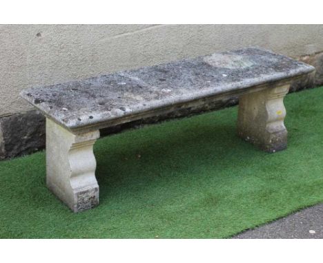 A CAST STONE BENCH, the moulded edged oblong seat raised on flower moulded square section end suppports each with shaped ogee