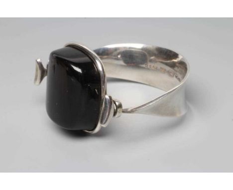 A GEORG JENSEN SILVER BANGLE designed by Vivianna Torun Bulow-Hube, the tension clamp centred by a polished smoky quartz, sta