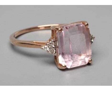 A KUNZITE AND DIAMOND DRESS RING, the oblong cut Kunzite claw set and with three small round brilliant diamonds to each shoul