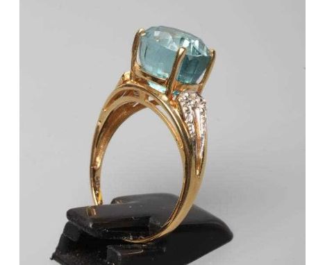 A BLUE TOPAZ COCKTAIL RING, the oval facet cut stone horizontally claw set to open bead shoulders point set with a small diam