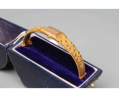 A 9CT GOLD STIFF HINGED BANGLE, the upper section gypsy set with a trefoil of three small diamonds flanked by panels applied 