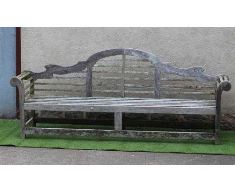 A LUTYENS STYLE SLATTED TEAK GARDEN BENCH with arched back and scrolled arms, raised on square section legs and stretchers, 1