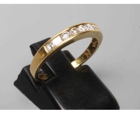 A SEVEN STONE DIAMOND HALF HOOP RING, the three round brilliants flanked by two pairs of square cut stones, all channel set t