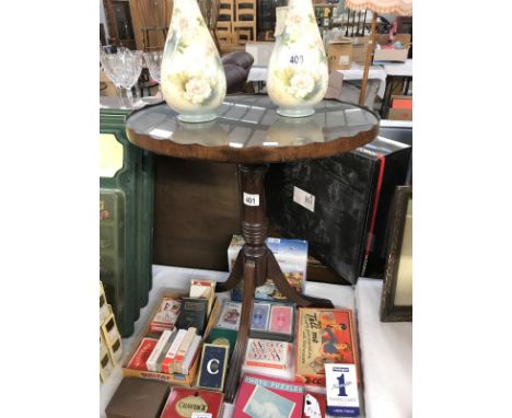 A dark wood stained oval tripod table with glass top