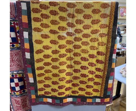 An Indian early 20th century multicoloured fabric quilt, with an embroidered central panel and printed cotton border, 115cm w