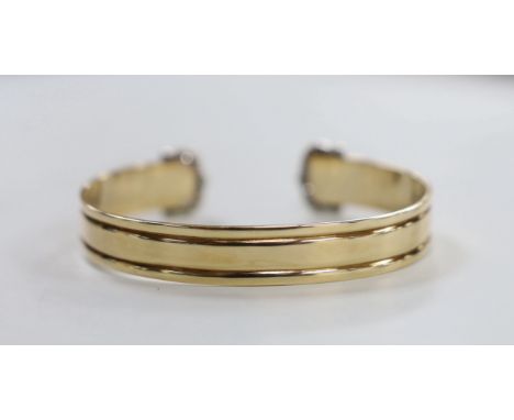 A yellow metal and diamond chip cluster set open work bangle, interior diameter approx. 66mm, gross weight 23.3 grams.