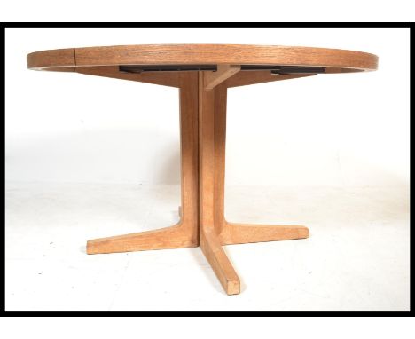 A vintage retro 20th century teak wood circular extending dining table raised on X base. Top removes from legs for ease of tr