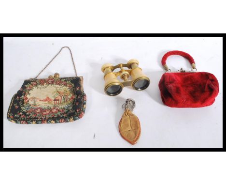 A vintage cased set of opera glasses in velvet purse together with a white metal and leather articulated purse and another. L