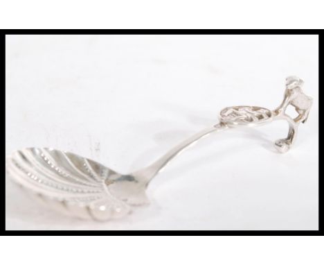 A silver hallmarked caddy spoon having shell bowl with pictorial plaque to handle depicting a Dutchman playing a French horn 