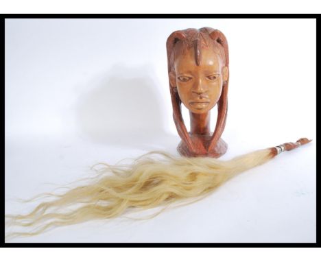 A vintage African carved tribal bust of a lady along with a horse hair fly whip having a carved handle. Measures 34 cm high a