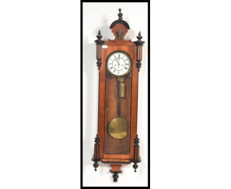 A vintage Vienna Regulator mahogany wall clock having turned columns and arched pediment. The white enamel face having a Roma