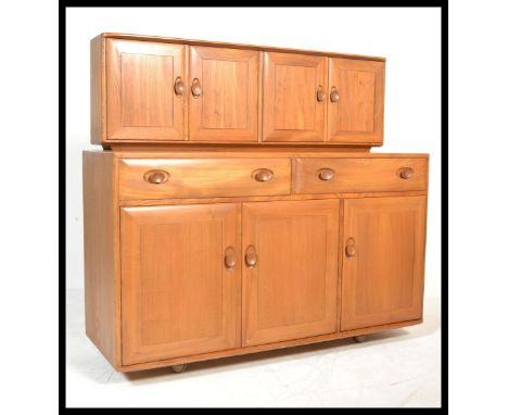 A vintage retro 20th century Ercol Beech and Elm sideboard highboard credenza unit. Raised on castors having three cupboards 