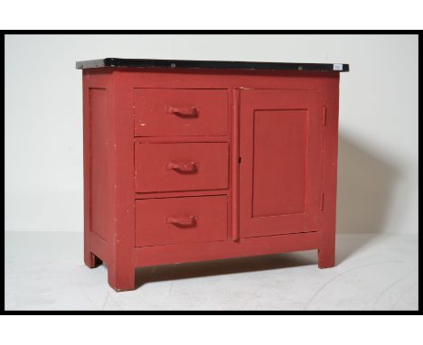 A vintage kitchen cabinet with a red formica top, 3 drawers to left and cupboard to right.
Enamel painted sliding top.&nbsp;M