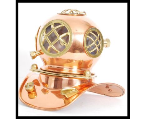 A vintage copper and brass desktop model of an antique deep sea divers helmet with clear acrylic panels behind metal cages.
