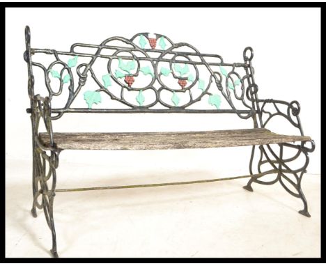 A vintage weathered garden bench having an ebonised cast iron back with painted leaf and vine decoration. Wooden slats betwee