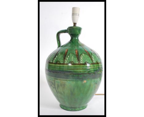 A vintage mid 20th century studio pottery lamp having a green glaze finish. The lamp of bulbous form with shaped handle to si