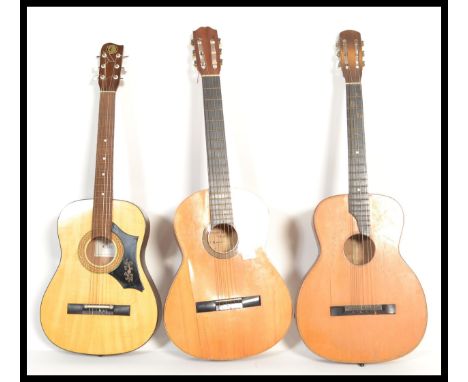 A group of three vintage acoustic six string guitars having shaped hollow bodies with paper labels to interior.