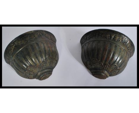A pair of heavy cast iron wall planter pockets having reeded bodies with grape and vine decoration. Measures 19 cm high, 29 c