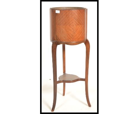An early 20th century Edwardian mahogany barrel planter jardiniere on splayed tripod legs with circular rack uniting the legs