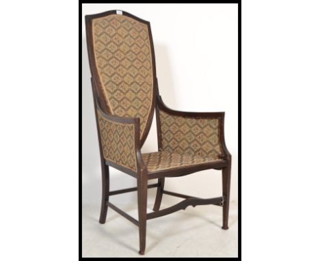 An early 20th century Edwardian mahogany fireside arm chair upholstered in tapestry with armorial shield back.