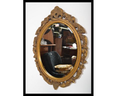 A vintage gilt surround oval wall mirror having an inset bevelled glass plate. The frame decorated with scrolls and acanthus 