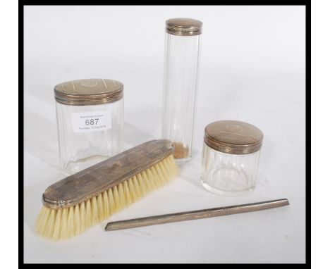 A set of silver hallmarked art deco dressing table items to include faceted glass pots , brush and comb cover having engine t