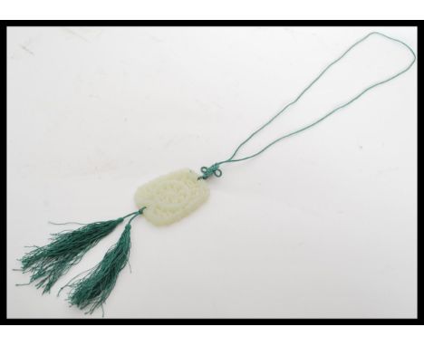 A Chinese carved jade double sided bi pendant having scrolled decoration on green thread necklace. Pendant measures measures 
