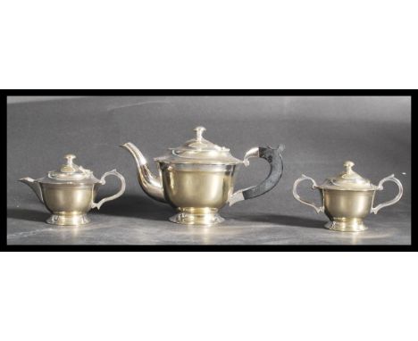An early 20th century silver plated three piece gents bachelors tea service having shaped scroll handles and finial lids.&nbs